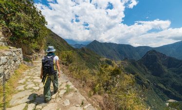 Backpacker exploring the steep Inca's footpaths of Machu Picchu, the most visited travel destination in Peru. Summer adventures in South America.