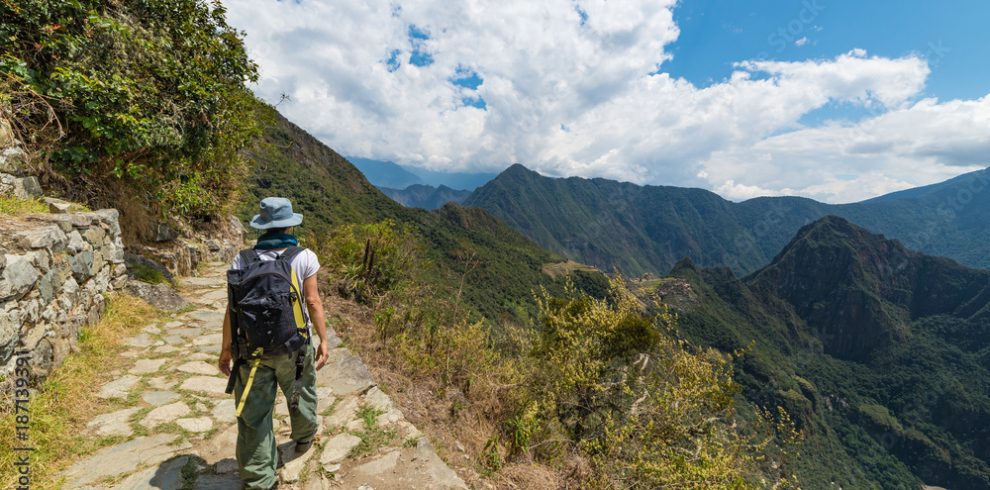 Backpacker exploring the steep Inca's footpaths of Machu Picchu, the most visited travel destination in Peru. Summer adventures in South America.