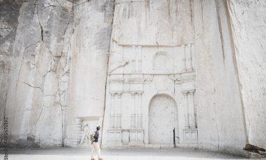 Wide angle view of a caucasian man looking at the stone wall sculpture of Petra in Ruta del Sillar, Arequipa, Peru.